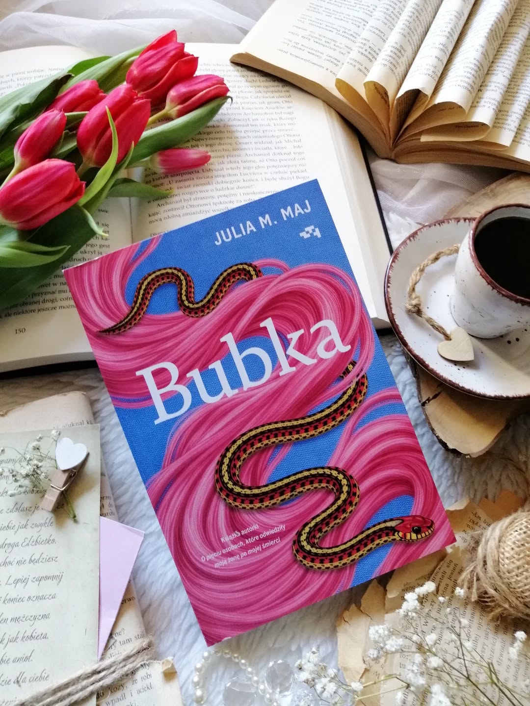 Dzień dobry 🤗  Historia, która zaskoczyła mnie swoją formą, niby jest lekko, momentami z humorem, a jednak nie do końca. Jest nietuzinkowa…  “Bubka” Julia M. Maj  Bubka nigdy nie miała łatwo, pracuje w budce z kurczakami, mieszka w małym pokoju w podupadłym pałacyku i ma dość nietypowego towarzysza, węża. Jej życie płynie powoli, mierzy się z kompleksami, samotnością i poczuciem, że nie radzi sobie z własną codziennością. Punktem zwrotnym stają się dramatyczne wydarzenia, śmierć ojca oraz napad, które wywracają jej świat do góry nogami. Wtedy pojawia się myśl o zmianie, o przewartościowaniu dotychczasowego życia i zwrócenia uwagi na własne potrzeby. Wtedy też na jej drodze pojawia się internetowy coach Dorian i jego kurs „Krąg Pięciu Zwierzęcych Przemian”.  Ujęła mnie autentyczność tej historii. 
I te fragmenty z perspektywy węża, przyjaciela Bubki 👌😉  Autorka z wyczuciem splata to, co bolesne, z tym, co wywołuje uśmiech, bawi się stereotypami. Humor jest tu subtelny, schowany między wierszami. Bohaterowie dalecy od ideału, bywają irytujący, popełniają błędy.  Porusza temat samotności, potrzeby akceptacji i trudności w byciu sobą w świecie pełnym oczekiwań. O wstydzie, o byciu niewidzialnym i o cichym pragnieniu, by w końcu ktoś nas zobaczył. O zmianie, która nie dzieje się sama. O odwadze, która rodzi się powoli, często w bólu i niepewności. Ukazuje, że żadna zmiana nie dzieje się z dnia na dzień, jak łatwo wpaść w pułapkę porównań i jak silnie wpływa to na nasze poczucie własnej wartości.  #bubka to życiowa, słodko-gorzka historia. Skłania do zatrzymania się na chwilę i refleksji. Polecam!  Współpraca barterowa - @wydawnictworelacja  Książka * jest pięknie * emocja * samotność * czytam * lubię czytać