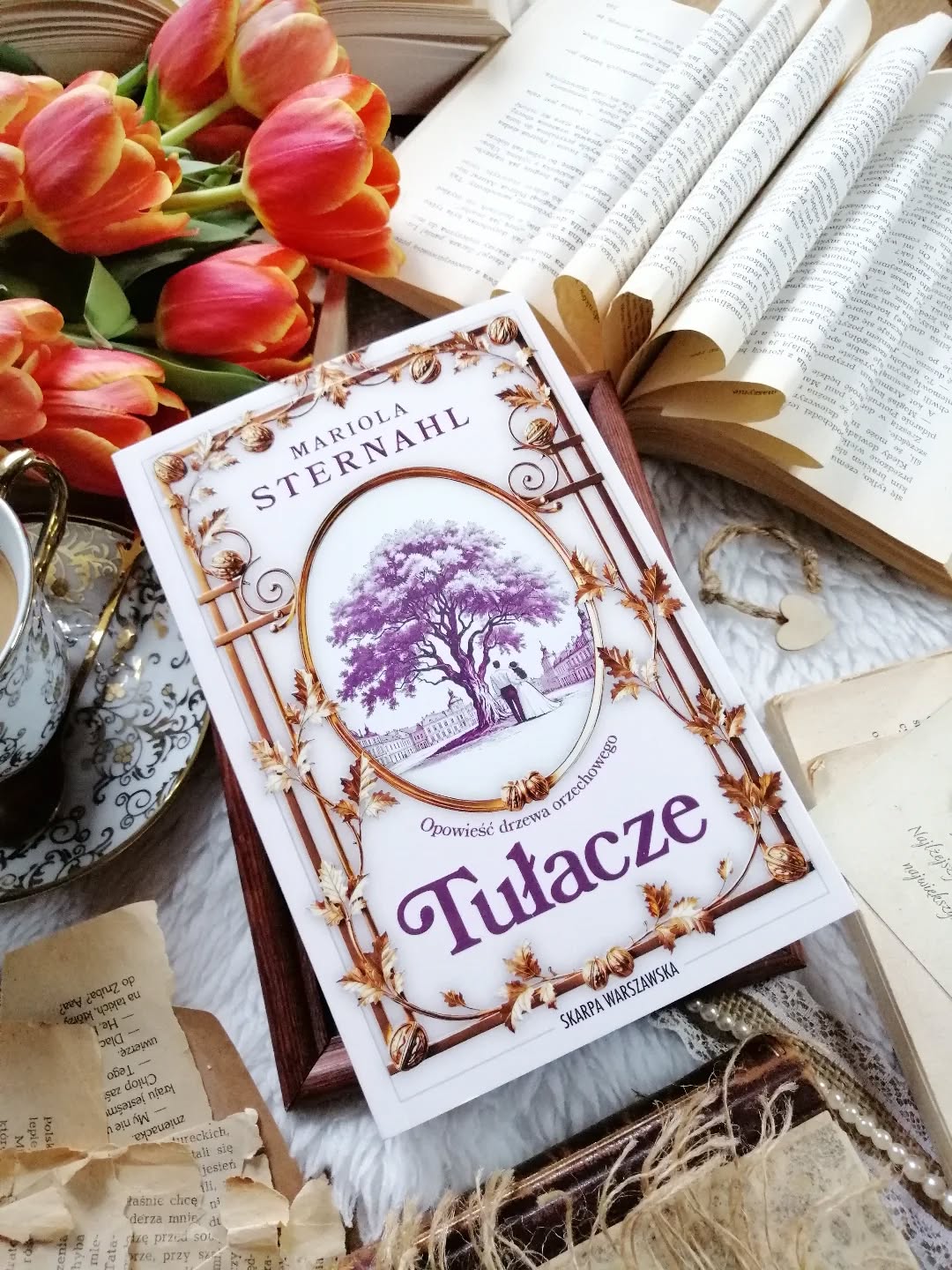 Dzień dobry 🤗  Nie jest to łatwa historia… i może właśnie dlatego zostaje w sercu na dłużej.  “Tamtej jesieni wszystko wydawało się możliwe. Nie widział jeszcze tylko, że wojna, która nadchodziła, nie pyta o marzenia ani o miłość”.  “Tułacze” Mariola Sternahl  Lwów, rok 1919. Polska podnosi się z wojennych ruin. W tym kruchym, niepewnym świecie splatają się losy dwóch rodzin — Orłowskich i Wojnarskich. Nie wiedzą jednak, jak wiele przyjdzie im poświęcić. Jak bardzo historia wkroczy w ich życie i odciśnie na nim swoje piętno.
Jan Orłowski, rzeźnik z dziada pradziada, zakochuje się w Helenie Wojnarskiej. Przez chwilę ich życie płynie spokojnie, zwyczajnie… niemal sielsko. Rodzą się synowie — Ignacy, August i Jarogniew. Codzienność ma swój rytm, a nad wszystkim czuwa stary orzech na dziedzińcu masarni, cichy świadek ich szczęścia. Widzi pierwsze kroki dzieci, drobne radości, ciepło rodzinnego domu. Ale zapamięta też to, co najtrudniejsze. Huk nadciągającej wojny, rozstania, które łamią serce, utratę tego, co wydawało się trwałe. Drogę, której nikt nie wybiera, a którą trzeba przejść.  Piękna, poruszająca opowieść, osadzona w trudnych czasach międzywojennych  i II wojny światowej.  Wielka historia spotyka się z codziennością zwykłych ludzi. Styl @mariolasternahl zachwyca! Jest w nim coś niezwykle kojącego, a jednocześnie przejmującego. Czuć ogrom pracy, wrażliwość i empatię.  Powieść wciąga cicho, z każdą stroną rośnie napięcie, pojawia się niepokój, lęk o jutro.  Historia o stracie i bólu, o nadziei, która choć krucha, nigdy do końca nie gaśnie. O synach porwanych przez bezlitosny wir wojny. O ziemi, która przechodzi z rąk do rąk. I o Lwowie — mieście, które tutaj żyje, porusza, zostaje w pamięci. Autorka prowadzi nas jego ulicami, pozwala zajrzeć w miejsca, których już nie ma. To także opowieść o miłości — tej między dwojgiem ludzi, tej rodzinnej, o miłości do tradycji, do miejsca, do ojczyzny. Miłości trudnej, często zranionej, pełnej łez. Trwającej mimo wszystko.  Jestem tą historią oczarowana. Poruszona.
 I bardzo czekam na ciąg dalszy. Serdecznie polecam. Więcej link w bio.  Współpraca barterowa - @skarpawarszawska  #tułacze #pięknaksiążka #powieść