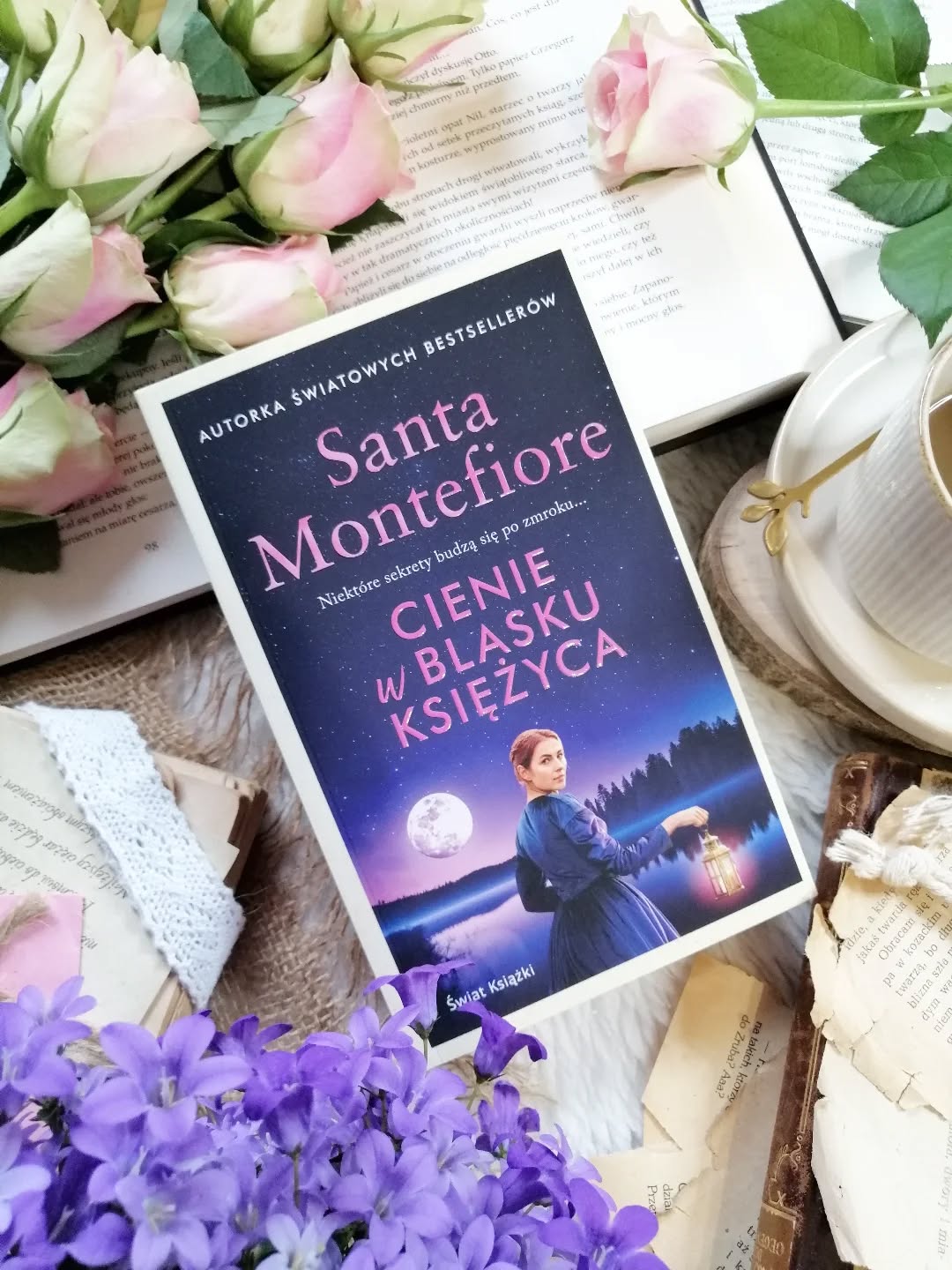 Dzień dobry 🤗  Interesujecie się ezoteryką?  „Cienie w blasku księżyca” Santa Montefiore  W starym, majestatycznym dworze stojącym na klifach Kornwalii młoda kobieta, Pixie Tate, natrafia na listy sprzed ponad stu lat. Ich lektura wciąga ją bez reszty i powoli odsłania historię wielkiej miłości, o której świat dawno już zapomniał. Z każdą kolejną stroną przeszłość zaczyna ożywać. Podążając śladami dawnych uczuć, Pixie odkrywa, że czasami to, czego najbardziej się obawiamy, jest jednocześnie tym, czego najbardziej potrzebuje nasze serce.  Autorka snuje nastrojową opowieść przepełnioną subtelną melancholią. 
Zarówno współczesna, jak i dziewiętnastowieczna Kornwalia została opisana naturalnie, barwnie, pięknie. Przyroda staje się cichym świadkiem dawnych dramatów i niemal równorzędnym bohaterem opowieści. Na tym tle wyraźnie wybrzmiewają wątki miłosne – pełne tęsknoty, straty i niedopowiedzeń. Bohaterowie mierzą się z trudnymi wyborami, wewnętrznym rozdarciem, ale także z obecnością kogoś, kto wciąż nie odnalazł ukojenia. Kluczową rolę w opowieści odgrywa Pixie, któa staje się medium. Jest przekonana że rozwiązanie tajemnicy kryje się w wydarzeniach sprzed lat.  Motyw zagubionej duszy autorka prowadzi z dużą wrażliwością. Nie jest on jedynie elementem budującym atmosferę tajemnicy, ale raczej symbolem niespełnionych marzeń, słów, które nigdy nie padły i ciężaru dawnych win.  Pozycja dla czytelników, którzy lubią opowieści otulone nutą rodzinnych tajemnic. W których granica między światem żywych i zmarłych staje się ledwo dostrzegalna. Polecam.  Współpraca barterowa - @wydawnictwo_swiatksiazki  #cieniewblaskuksiężyca #powieść #książka #czytamzawsze #czytanie