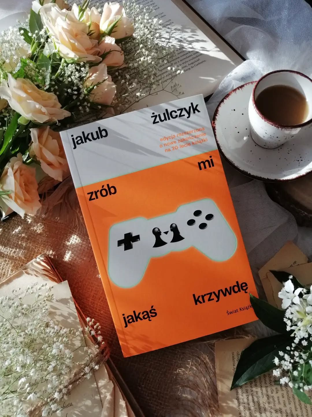 Dzień dobry 🤗  Dwadzieścia lat od premiery!  „Zrób mi jakąś krzywdę” Jakuba Żulczyka wciąż pozostaje zaskakująco aktualną powieścią. To historia, która mimo upływu czasu nie straciła swojej siły i nadal trafnie pokazuje zagubienie młodych ludzi oraz ich próby odnalezienia własnego miejsca w świecie pełnym chaosu.  Dwudziestopięcioletni Dawid zakochuje się w piętnastoletniej Kaśce, siostrze swojego najlepszego przyjaciela. Dziewczyna wyraźnie wyróżnia się na tle rówieśników. Żyje światem gier komputerowych, myśli nieszablonowo i patrzy na rzeczywistość z zupełnie innej perspektywy. To, co początkowo wydaje się niewinnym zauroczeniem, bardzo szybko wymyka się spod kontroli i prowadzi do wydarzeń, których trudno byłoby się spodziewać...  Podczas lektury trudno nie dostrzec, jak uważnym obserwatorem ludzi jest Żulczyk. Z dużą przenikliwością pokazuje emocje, słabości i motywacje swoich bohaterów, nie oceniając ich i nie narzucając czytelnikowi gotowych odpowiedzi.  #zróbmijakąśkrzywdę to opowieść o samotności, wewnętrznych rozterkach i nieustannej próbie ucieczki przed własnymi lękami. Relacja bohaterów staje się jedynie punktem wyjścia do pokazania znacznie głębszych emocji i problemów. Pojawiają się kolejni bohaterowie, każda z nich wnosi do tej historii coś innego, jedne dostarczają humoru, inne ironii, a jeszcze inne skłaniają do refleksji nad absurdami codzienności i współczesnego świata.  Historia mocno osadzona w świecie muzyki, gier komputerowych i popkultury, a jednocześnie poruszająca emocje, które pozostają uniwersalne niezależnie od czasu. Nie brakuje tu ciętego humoru, gorzkich momentów i celnych obserwacji.  Przede wszystkim jest to jednak opowieść o ludziach, niedoskonałych, zagubionych,  prawdziwych. Chwilami niewygodna, momentami prowokująca, wywołująca skrajne emocje.To jedna z tych książek, które nie dają prostych odpowiedzi, za to na długo pozostają w pamięci.  Bardzo polecam!  Współpraca barterowa - @wydawnictwo_swiatksiazki  polecam * młodość * samotność * uczucia * czytam f książki * literatura * dobra książka