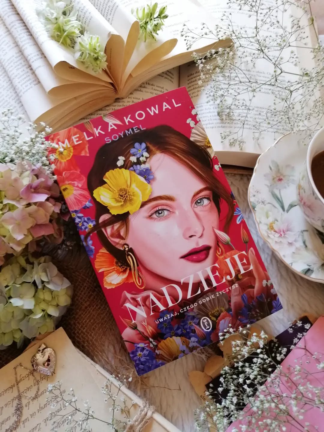 Dzień dobry 🤗  Wciągająca powieść obyczajowa z miłosnymi zawirowaniam i sporą dawką dobrego humoru.  “Największe zmiany zaczynają się od spojrzenia w głąb siebie”.  „Nadzieje” Melki Kowal to czwarty, a zarazem finałowy tom serii „Maski”.  Erin jest autorką gorących, poczytnych romansów. W życiu prywatnym nie ma tyle szczęścia, co bohaterowie jej książek. Za sobą ma bolesne doświadczenia i kilka miłosnych rozczarowań. Największe rany pozostawili mężczyźni, którym zaufała, a szczególnie Blake, który przed laty złamał jej serce. Gdy do tego dochodzi twórczy kryzys, Erin podejmuje zaskakującą decyzję, zgłasza się do programu prowadzonego przez słynną swatkę. Rodzinna tragedia sprawia, że chce wycofać się z programu, ale jest już za późno. Niespodziewane spotkanie z Blake'em wywraca jej świat do góry nogami. Dawne uczucia odżywają, wracają wspomnienia. Między bohaterami zostaje zawarte porozumienie, które staje się początkiem wydarzeń pełnych napięcia…  @s0ymel pisze lekko i z ogromną swobodą, a przy tym doskonale wyważa humor i emocje. Dialogi są naturalne, błyskotliwe i pełne życia, a zabawne sceny płynnie przeplatają się z tymi bardziej poruszającymi.  Z zainteresowaniem śledziłam losy Erin, kibicowałam jej i razem z nią przeżywałam wszystkie wzloty oraz upadki. To bohaterka nieidealna, impulsywna, czasem błądząca. Łatwo zrozumieć jej emocje i wybory, a chwilami nawet odnaleźć w niej cząstkę własnych doświadczeń.  #nadzieje to opowieść o miłości, przebaczeniu, przyjaźni i odwadze, by ponownie otworzyć serce. O relacjach  z drugim człowiekiem i z samym sobą. To historia pokazująca, że zanim nauczymy się kochać innych, warto najpierw zaakceptować siebie, wsłuchać się i zrozumieć własne potrzeby. To także opowieść o drugich szansach, trudnych wyborach i ludziach, którzy mimo życiowych zawirowań wciąż mają odwagę walczyć o swoje szczęście.Tak trudno ponownie zaufać drugiemu człowiekowi, gdy zostało się dotkliwie zranionym.  Ciepła, pełna uroku i wzruszeń historia, która skłania do refleksji.  Bardzo polecam!