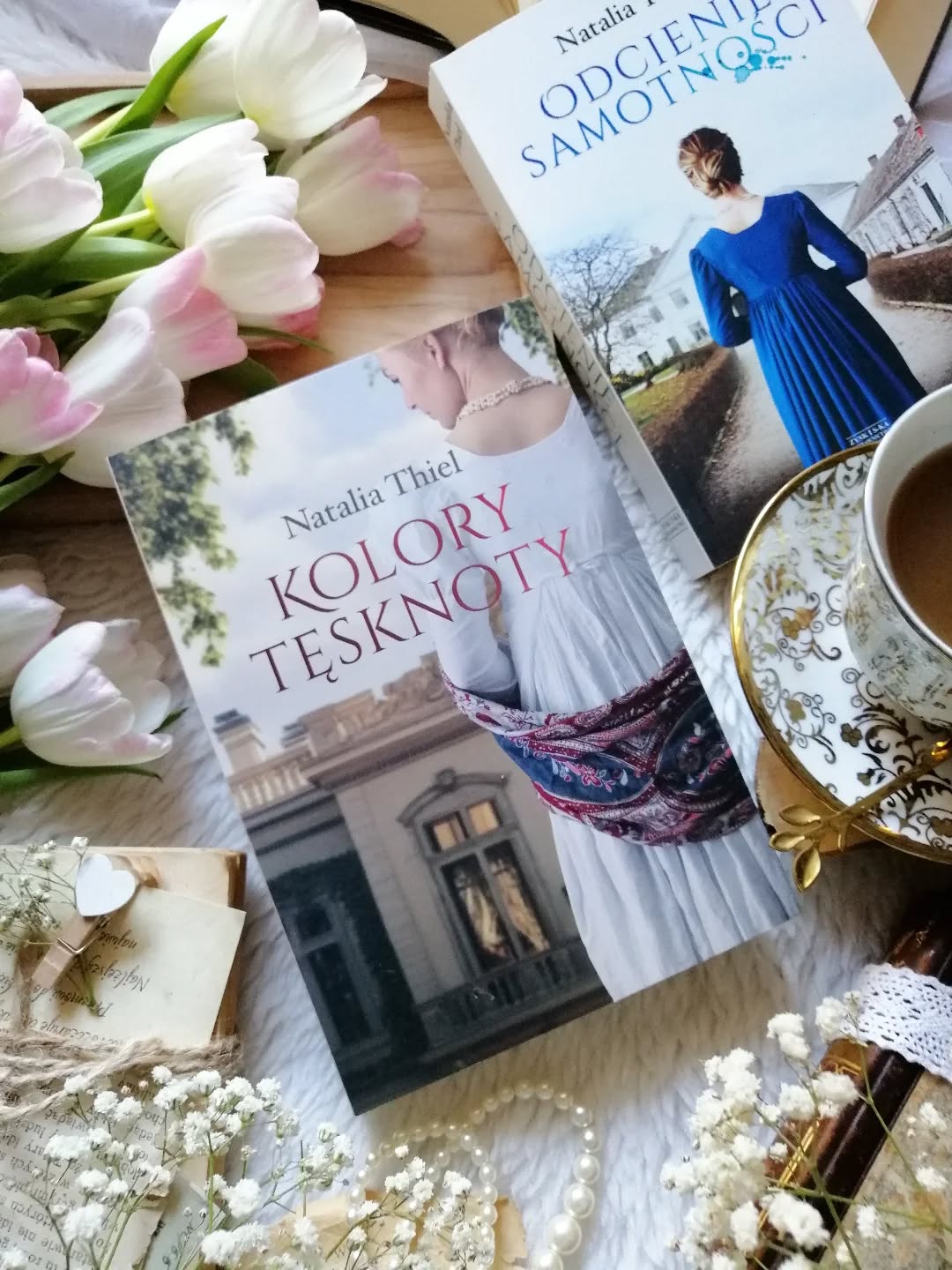 Dzień dobry 🤗  Pomiędzy tym, co wypada, a tym, czego naprawdę pragnie serce…  “Każdy kto żyje z brzemieniem kłamstwa, wie, jak trudne jest ono do udźwignięcia i jak wiele ryzykuje się każdego dnia”.  “Kolory tęsknoty” Natalii Thiel  Poruszająca opowieść o dalszych losach bohaterek znanych z “Odcieni samotności”. 
Po śmierci Amelii świat bohaterów zmienia się nie do poznania. To, co kiedyś było bliskością i siostrzaną więzią między Wiktorią a Luizą, dziś zamienia się w chłód i niedopowiedzenia. Miłość do tego samego mężczyzny odciska piętno, którego nie sposób zatrzeć. Każda z nich próbuje odnaleźć się w nowej rzeczywistości, podejmując decyzje, które mają przynieść spokój… a przynoszą rozczarowanie i samotność.  To historia o wyborach, które nigdy nie są proste, o uczuciach, które nie zawsze mają prawo wybrzmieć, i o tęsknocie, która potrafi towarzyszyć człowiekowi przez całe życie. O kobietach, które żyją w świecie pełnym zasad, konwenansów i oczekiwań. Które uczą się milczeć, bo przecież „nie wypada” mówić o bólu.  Natalia Thiel z wrażliwością prowadzi czytelnika przez tę historię. Jej styl jest lekki, naturalny, a jednocześnie pełen emocji i subtelności. Z ogromną dbałością o detale odtwarza realia XIX wieku – świat podziałów społecznych, konwenansów i ograniczeń, w którym kobiece serce często musiało podporządkować się rozsądkowi i oczekiwaniom innych.  Atutem tej powieści jest jej klimat – elegancki, spokojny, a jednocześnie przesycony napięciem, które wyczuwa się tuż pod powierzchnią. To historia, która płynie niespiesznie, ale bardzo angażuje. Sprawia, że zaczynamy czuć razem z bohaterami – ich rozgoryczenie, tęsknotę, bezsilność i nadzieję, która mimo wszystko nie gaśnie.  To także piękna opowieść o miłości wystawionej na próbę, o relacjach, które pękają pod ciężarem tajemnic, i o tym, że czasem najtrudniejsze decyzje stają się początkiem najważniejszych zmian.  #kolorytęsknoty to książka pełna emocji, sekretów i cichych dramatów ukrytych za codziennością. Bardzo polecam, więcej - link w bio - zapraszam.  współpraca barterowa - @zysk_wydawnictwo  #nataliathiel #bookstagrampolska #czytelniczka #emocjewksiążkach