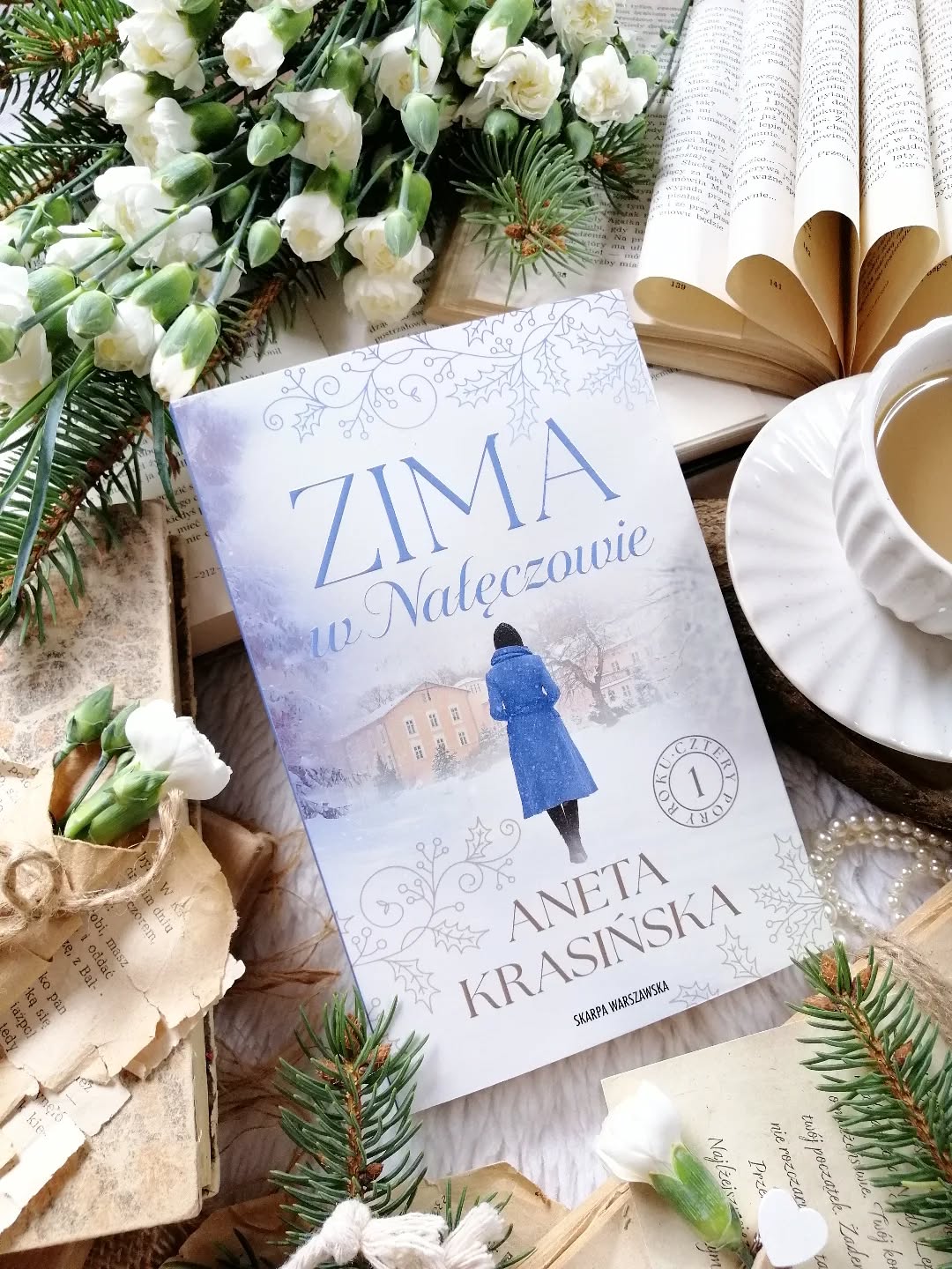 Dzień dobry 😊  Czasem to, co wydaje się końcem, okazuje się początkiem zupełnie nowej drogi…  “Czasem jest niewidoczne to, co mamy pod nosem”.  “Zima w Nałęczowie” Aneta Krasińska  Wciągający pierwszy tom cyklu “Cztery pory roku”, przyjemność z czytania ogromna.  Lidka żyje w ciągłym pośpiechu. Praca daje satysfakcję, a życie osobiste wydaje się poukładane — kocha i jest kochana. Z narzeczonym planują ślub, wspólnie urządzili mieszkanie, spłacają kredyt. Wszystko wygląda na idealnie dopasowaną codzienność. Do czasu… gdy Lidka niespodziewanie przyłapuje ukochanego na zdradzie. W jednej chwili jej świat się rozpada. Zraniona i zagubiona, szuka ukojenia u przyjaciółki. Za jej namową wyjeżdża do Nałęczowa — miejsca, które ma pomóc jej odzyskać równowagę. Tam, wśród ciszy i zimowego spokoju, Lidka z ciekawością poznaje nowe otoczenie. Przez przypadek trafia na drogocenną biżuterię i postanawia odnaleźć jej właściciela. Nie przypuszcza, że to odkrycie otworzy przed nią drzwi do przeszłości, a historia przedwojennego Nałęczowa tak bardzo ją zafascynuje, że zapomni o własnych troskach…  Wciągająca historia, która płynie spokojnym rytmem, poruszając i wzruszając zarazem. Fabuła została poprowadzona z wyczuciem — teraźniejszość współgra z przeszłością czasów II wojny światowej, a wątki splatają się, tworząc pełen emocji obraz ludzkich losów.  Klimatyczna, pełna emocji powieść, otulona zimową scenerią i cichym blaskiem refleksji. To historia, w której przeszłość splata się z teraźniejszością, a podjęte kiedyś decyzje niosą konsekwencje dla dnia dzisiejszego.  To opowieść o miłości, która nie powinna się wydarzyć, o zawiedzionych nadziejach, o nienawiści potrafiącej zatruć życie. I o teraźniejszości – o zdradzie, która rani, o sercu próbującym uleczyć się po stracie, o delikatnej nadziei, która tli się mimo wszystko.  Emocjonująca historia, która skłania do refleksji i otula czytelnika ciepłem. Czekam na dalsze losy bohaterki i jej bliskich. Polecam, na więcej zapraszam recenzja link w bio.  [współpraca barterowa - @skarpawarszawska]  #powieść #polecam #literatura #książka #dzieńzksiążką #ksiazkitopasja #czytamzawsze #czytanie #zimawnałęczowie